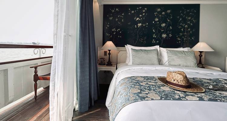 Cozy bedroom on a river cruise ship with a hat on the bed.