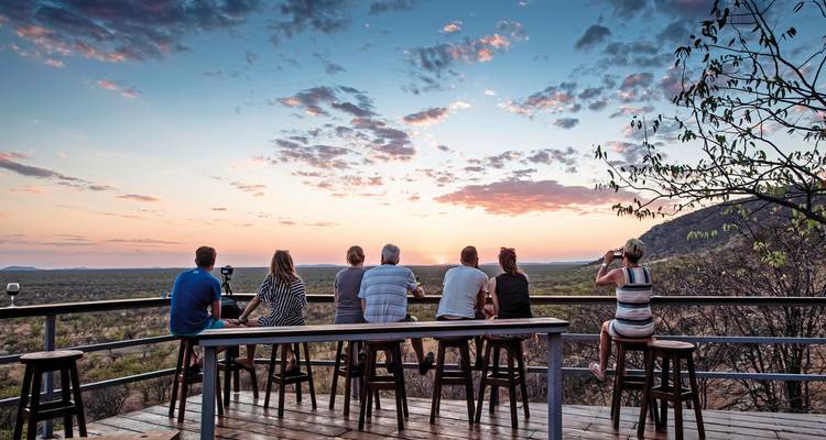 Group of people watching a sunset from a deck.