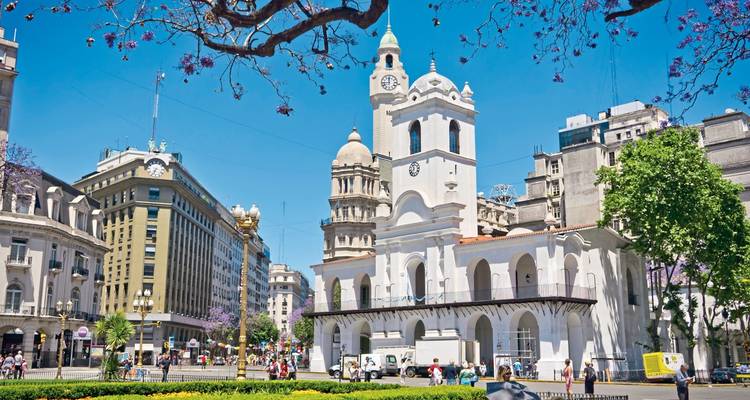 Weißes Gebäude mit Uhrenturm in einer Stadtszene