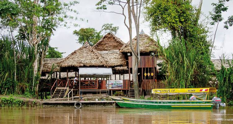Rustikale Hütten am Flussufer mit einem nahegelegenen Boot am Steg.