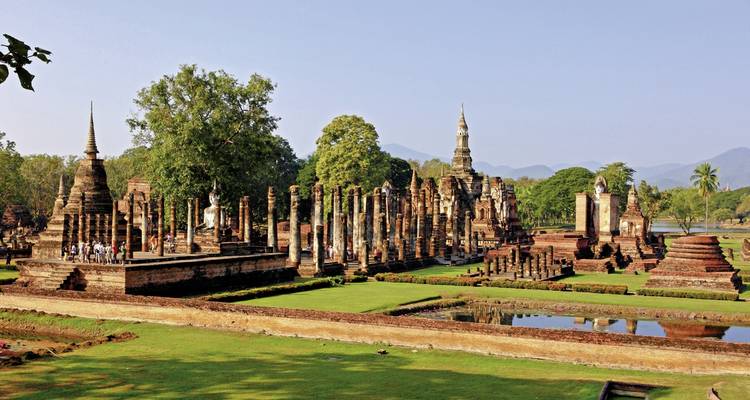 Anciennes ruines de pierre avec des structures semblables à des stupas situées dans un paysage verdoyant.