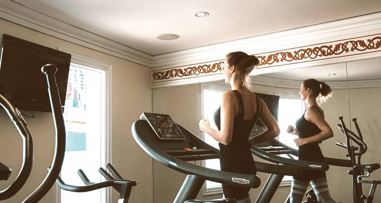 Fitnessstudio auf einem Kreuzfahrtschiff mit einer Frau, die auf einem Laufband trainiert.