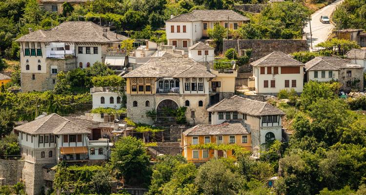 Vista elevada de casas de piedra otomanas tradicionales agrupadas en una ladera en Gjirokastra.