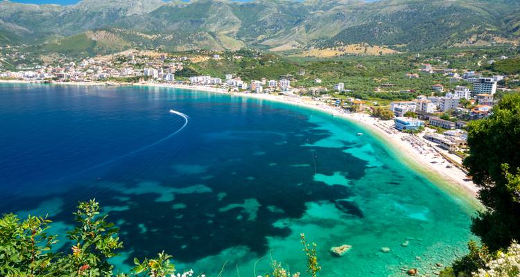 Una vista aérea impresionante de una bahía azul profundo y aguas turquesas poco profundas en el pueblo de Himara en la Riviera Albanesa.