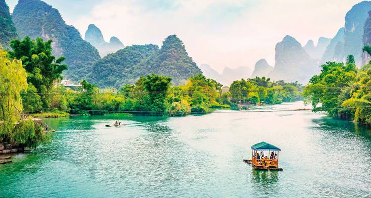 Río con una balsa de bambú y montañas brumosas de fondo en Yangshuo.