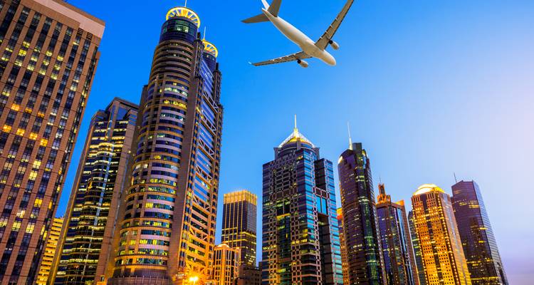 Moderne wolkenkrabbers van Shanghai bij schemering met een vliegtuig dat overvliegt.