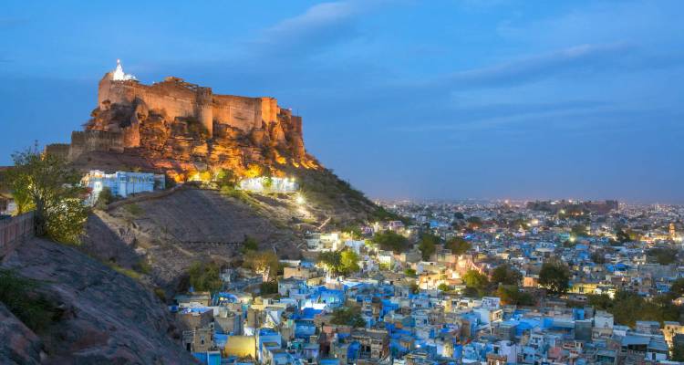 Le Fort Mehrangarh illuminé surplombant les maisons peintes en bleu de Jodhpur au crépuscule.