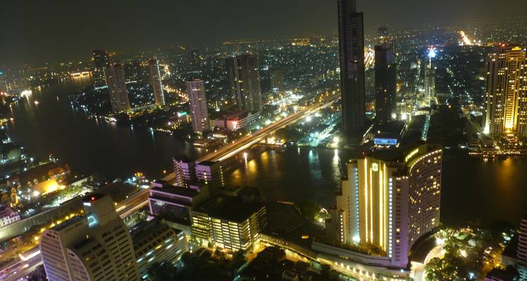 Hochfliegende Nachtaufnahme über Bangkoks Skyline und dem beleuchteten Chao-Phraya-Fluss.