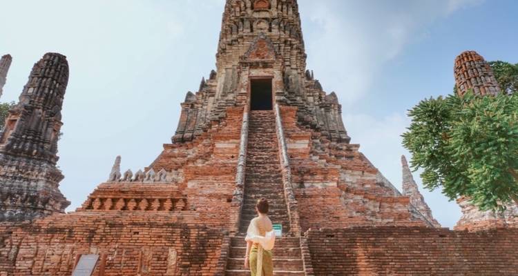 Eine Frau, die vor einem majestätischen antiken Tempel mit großen Treppen steht.