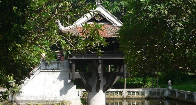 Eine kleine Pagode auf Stelzen über dem Wasser in einem Garten.
