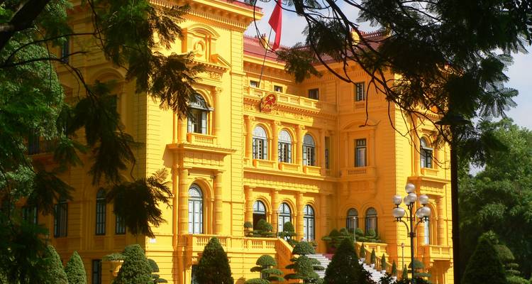 Ein strahlend gelbes Kolonialgebäude in einer Gartenanlage.