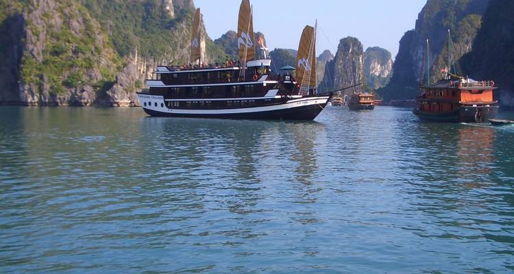 Ein Ausflugsboot, das durch Kalkstein-Karst auf klarem, blauem Wasser navigiert.