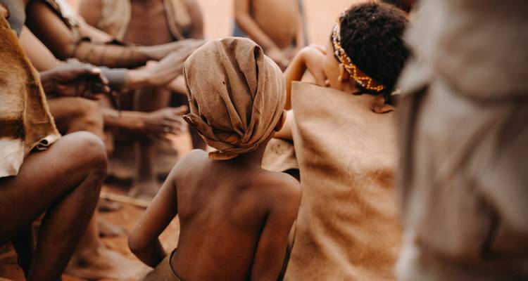 Les enfants Himba se rassemblent étroitement lors d'une activité traditionnelle à la lumière chaude du désert.