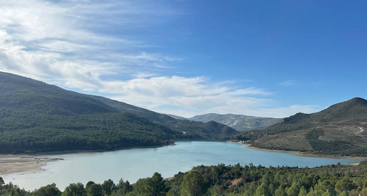 Une vue sereine d'un lac entouré de paysages vallonnés and d'arbres.