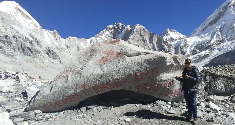 Everest Base Camp sign on a large boulder with mountains in the background.