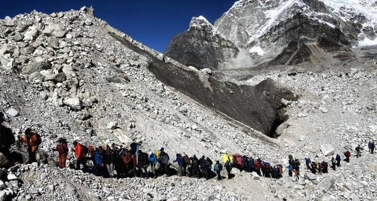 Line of hikers on a rocky mountain trail.