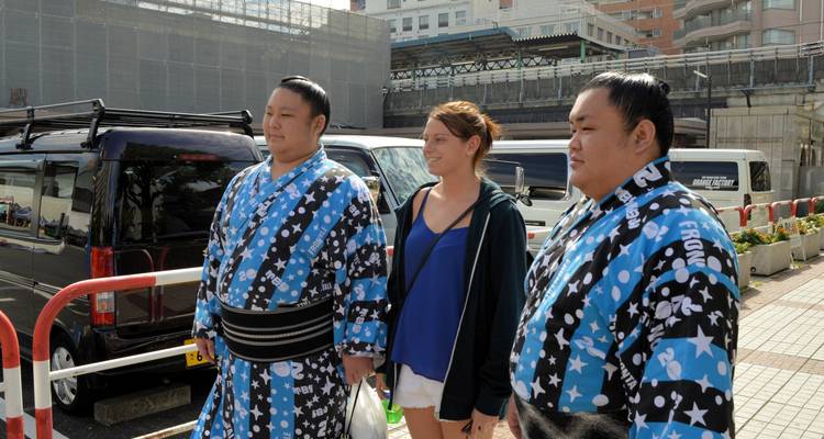 Zwei Männer in traditioneller Kleidung mit einer Frau auf einer Straße.