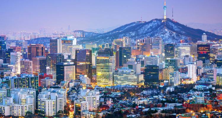 Panoramablick auf die Stadtlandschaft von Seoul mit dem Namsan-Turm und schneebedeckten Hügeln.