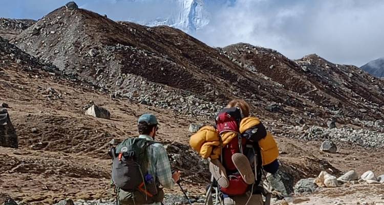 Wandelaars met rugzakken die langs bergachtig terrein lopen.