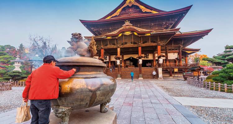 Man placing incense in a pot at a temple entrance