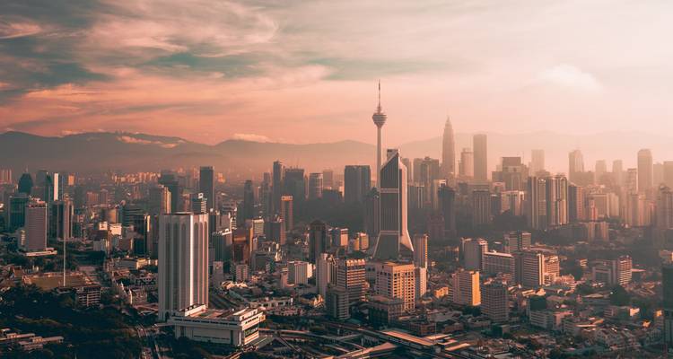 Stadshorizon met de Kuala Lumpur Tower en omringende moderne gebouwen tijdens zonsondergang.