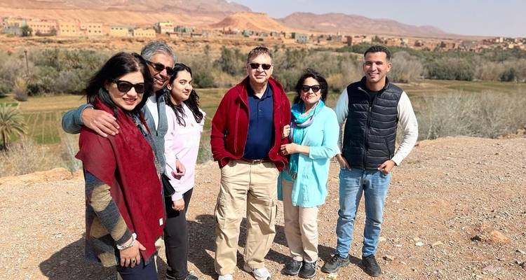 Gruppe von sechs Personen, die vor einer malerischen Tallandschaft im Hintergrund posieren.