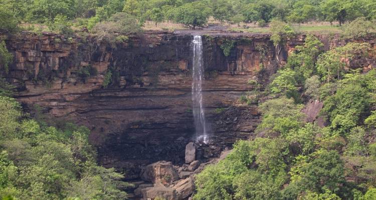 Wasserfall, der eine felsige Klippe hinunterstürzt, umgeben von üppigem Grün.