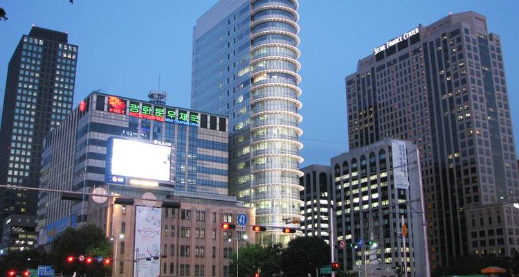 Paysage urbain en soirée du quartier d'affaires aux gratte-ciel de Séoul avec des enseignes illuminées et des feux de circulation.