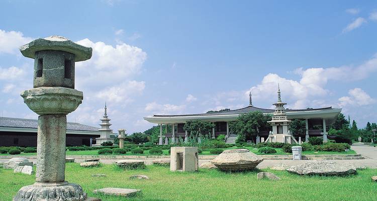 Stenen lantaarns en pagoda's op verzorgde gazons naast een modern tentoonstellingsgebouw in Gyeongju.