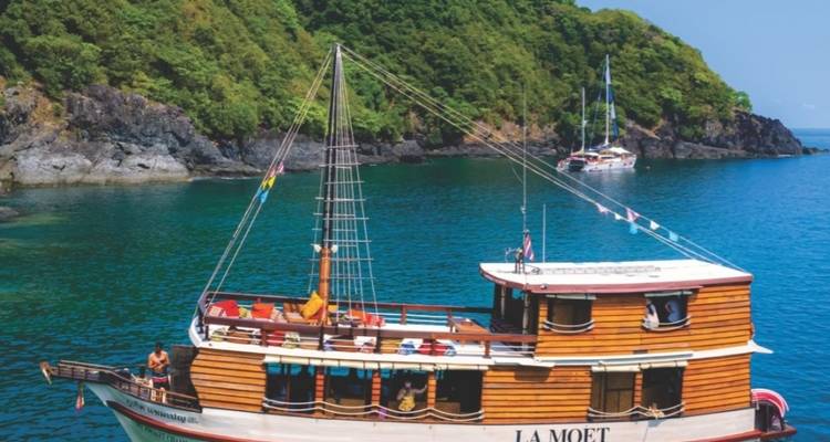 Segelboot namens 'LA MOET' in der Nähe einer tropischen Insel.