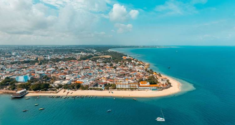 Küstenstadt mit einem Sandstrand und klarem blauen Wasser.
