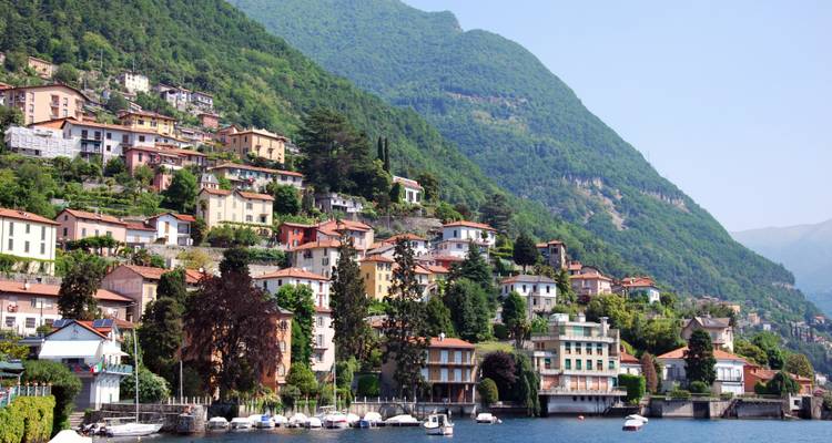 Charming hillside houses near water in a green landscape.