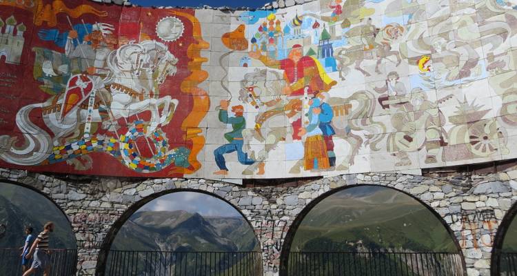 Fresque colorée et plateforme d'observation avec des montagnes en arrière-plan.