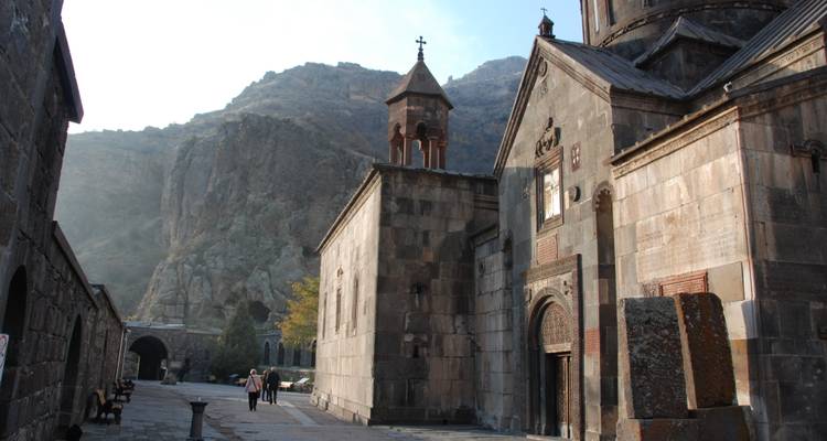 Ancien monastère en pierre sur fond de montagnes.