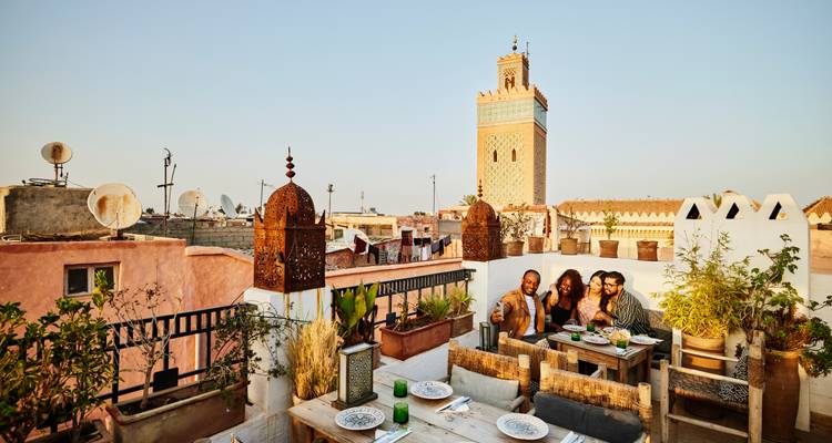 Gruppenessen auf einer Terrasse mit Blick auf die Skyline von Marrakesch.