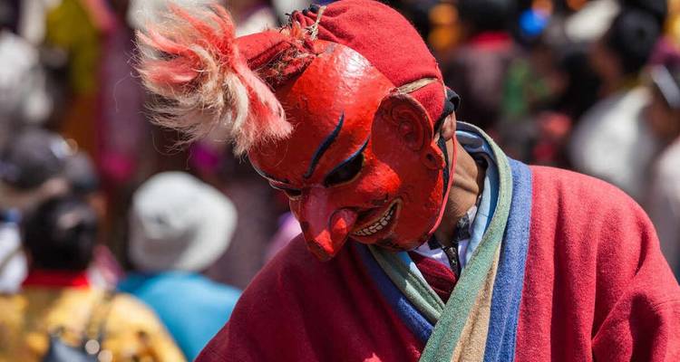 Un gros plan d'un artiste portant un masque rouge lors d'un festival.