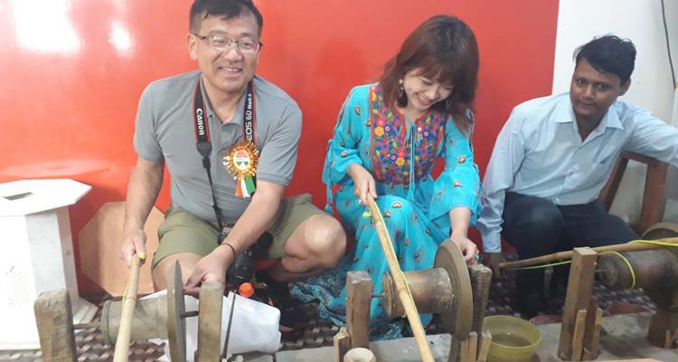Visitors try traditional handicraft using foot-powered stone wheels inside a workshop.
