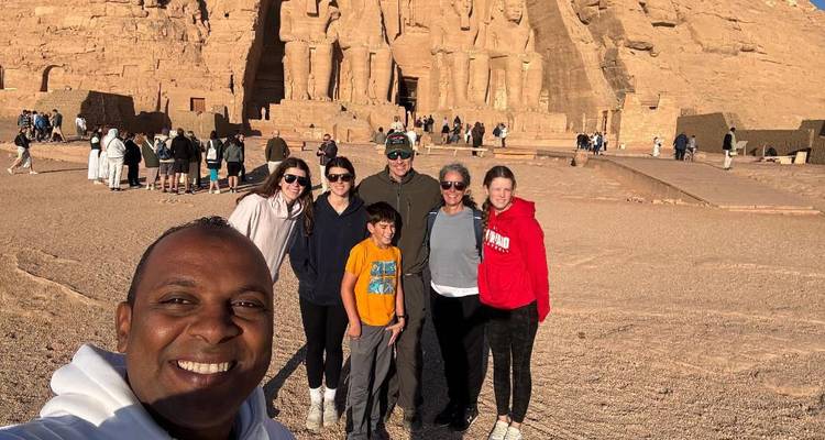 Un groupe familial sourit devant les statues monumentales taillées dans la roche d'Abou Simbel.