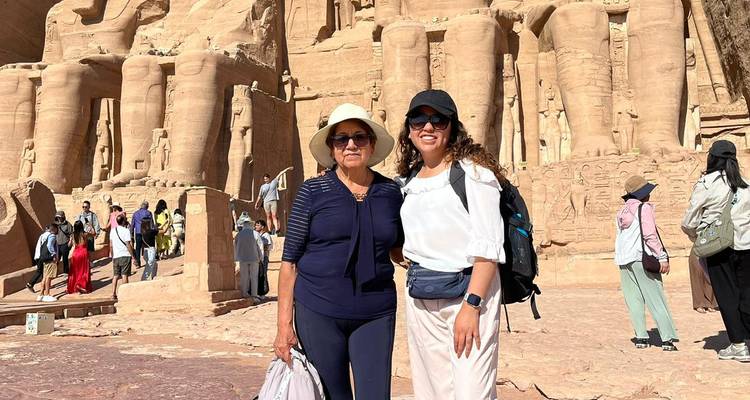 Deux femmes posent devant les statues colossales d'Abou Simbel par une journée ensoleillée.