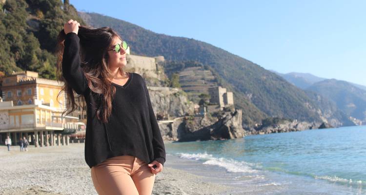 Frau posiert am Strand mit malerischen Hügeln im Hintergrund