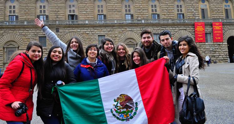 Group of people holding a flag in front of a historic building.