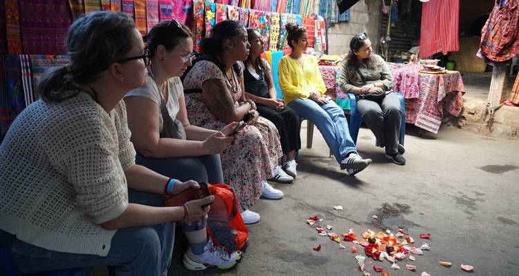Groep mensen zittend bij kleurrijke textiel.