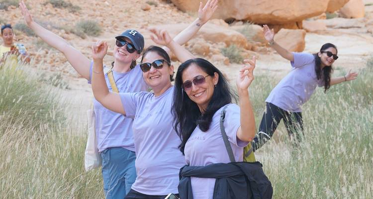 Femmes en équipement de randonnée prenant des poses ludiques dans une zone rocheuse.