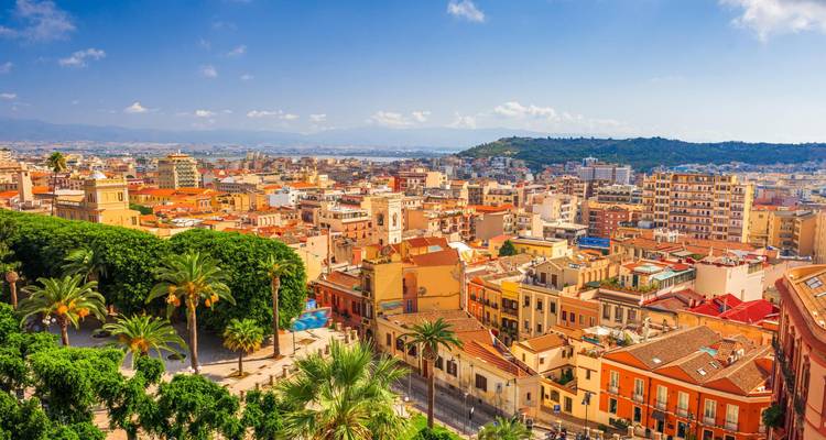 Vue aérienne lumineuse de la ville de Cagliari avec des palmiers, des bâtiments colorés et une baie lointaine