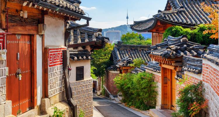 Traditional Korean Hanok village with a tower in the background.