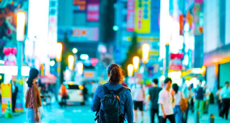 A bustling city street with bright neon lights at night.