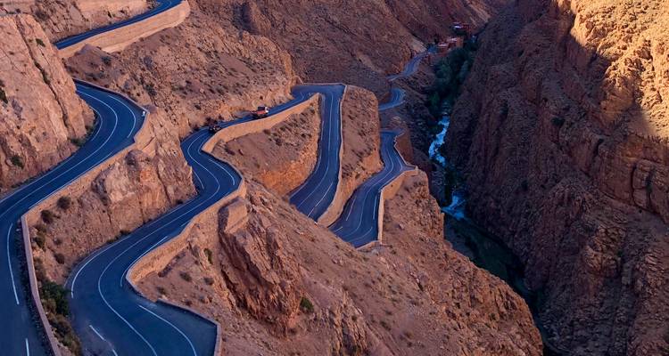 Winding road through rocky landscapes with a small river visible.