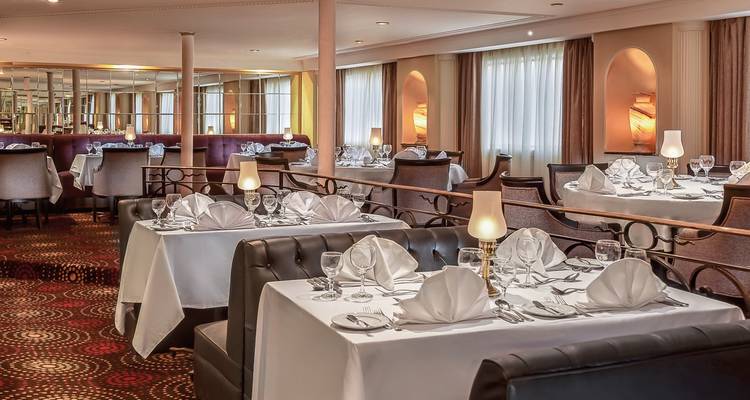 Salle à manger élégante avec des tables dressées pour un repas sur un bateau de croisière.