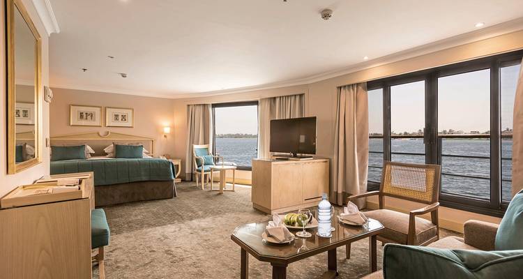 Cabine spacieuse de bateau de croisière avec de grandes fenêtres donnant sur un plan d'eau.