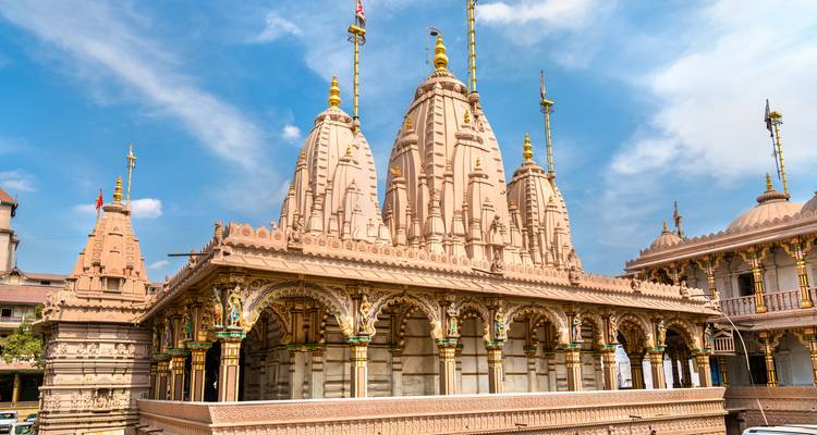 Templo jainista intricadamente tallado con múltiples torres contra un cielo azul brillante.